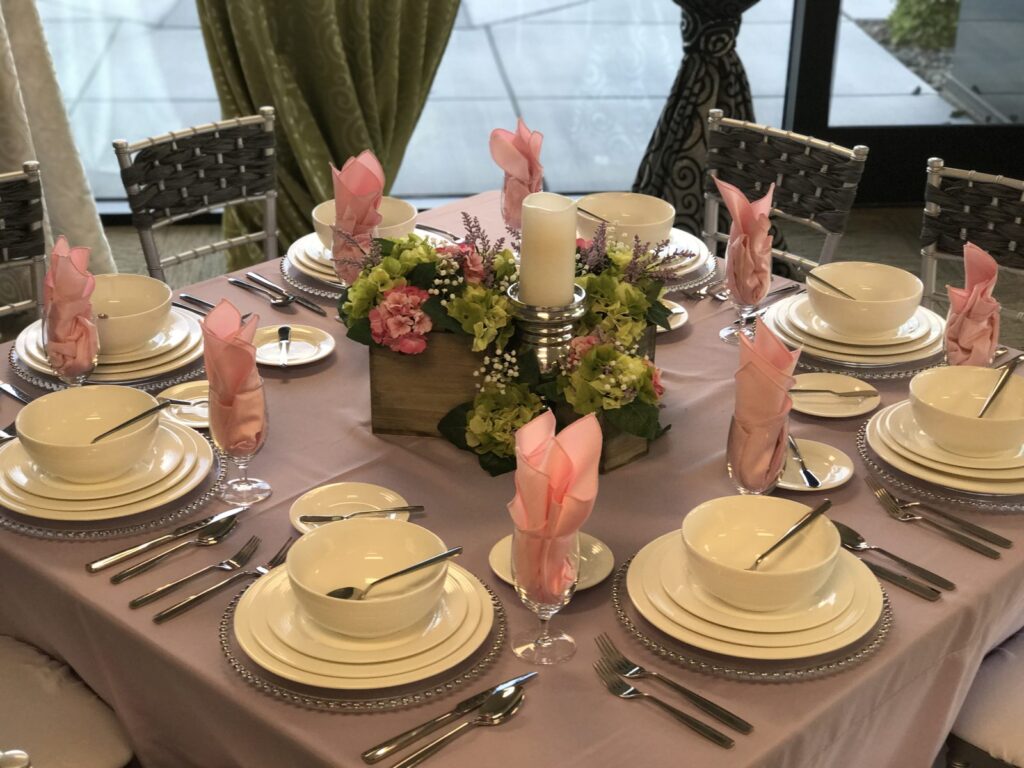 Fully set 100-guest event table with Chiavari chairs, silver chargers, china, and linens under a tent in Las Vegas