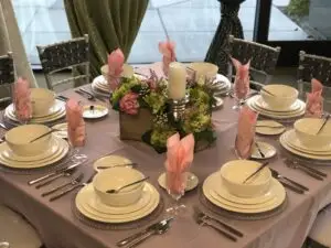 Fully set 100-guest event table with Chiavari chairs, silver chargers, china, and linens under a tent in Las Vegas
